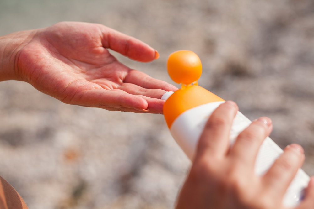 person putting on sunscreen at the beach.